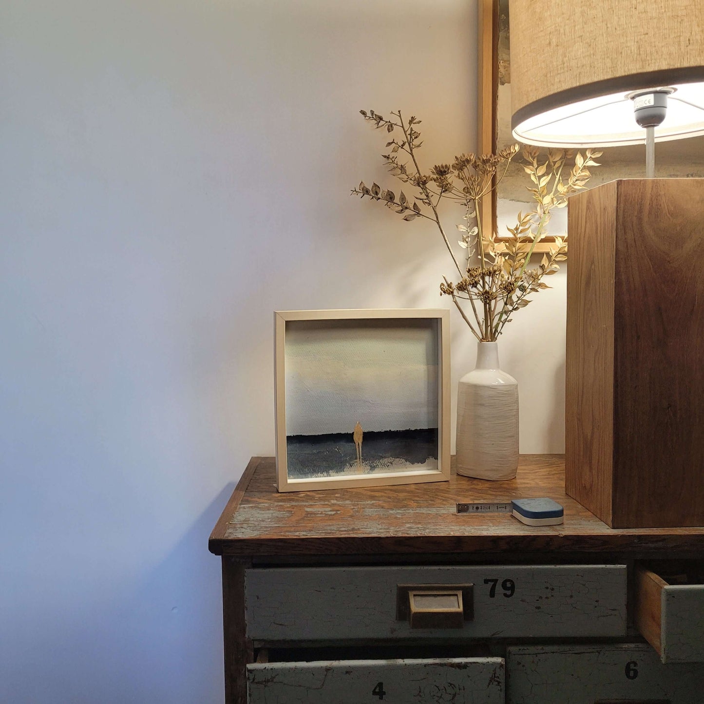 oeuvre acrylique Nature humaine 4 sur une commode en bois avec une lampe et un vase décoratif.